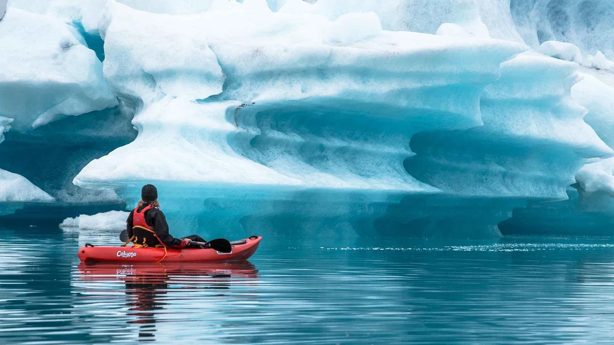 Kayakers paddling past floating icebergs on a Jökulsárlón glacier lagoon kayaking tour in Iceland